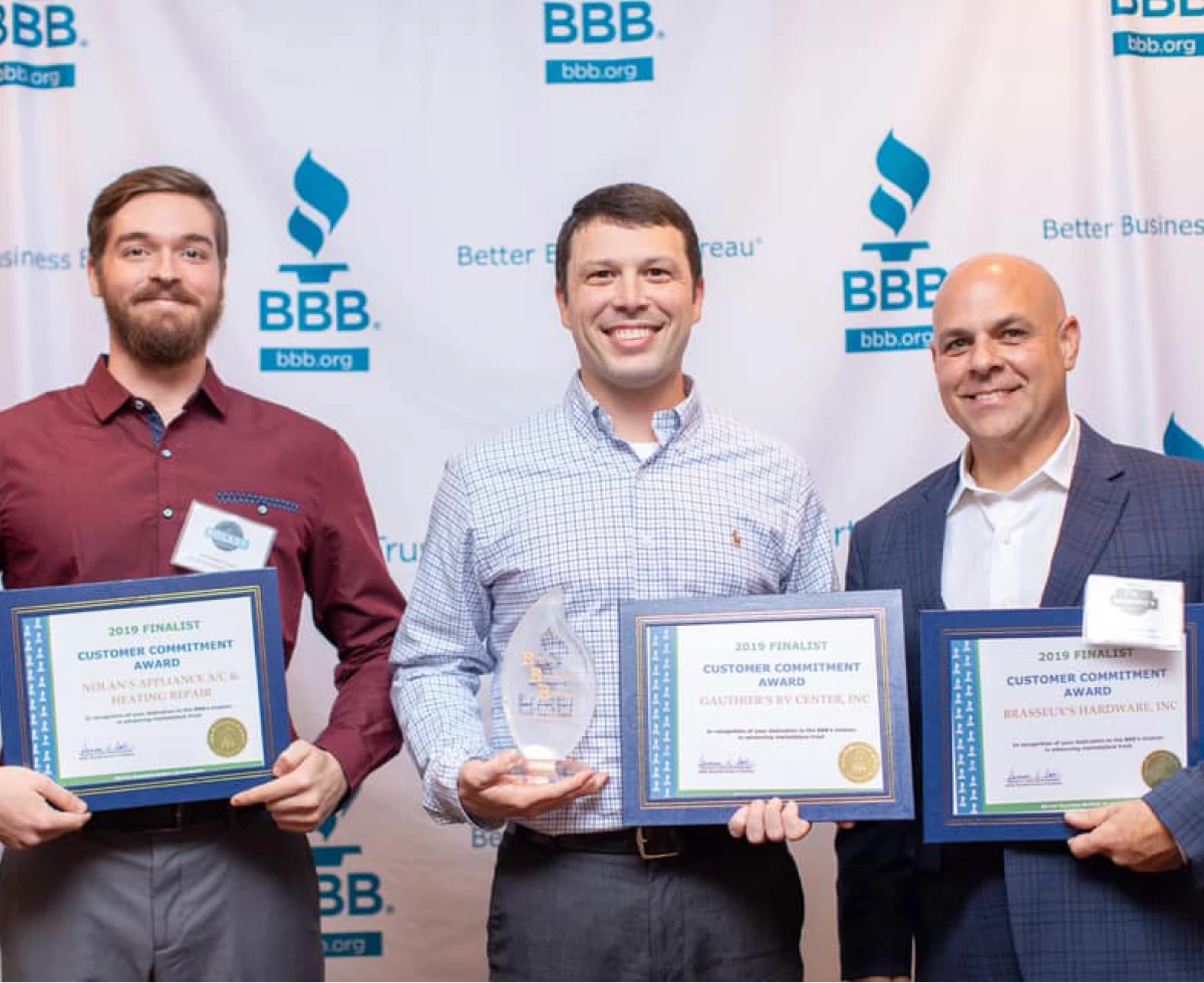Three men holding awards at event
