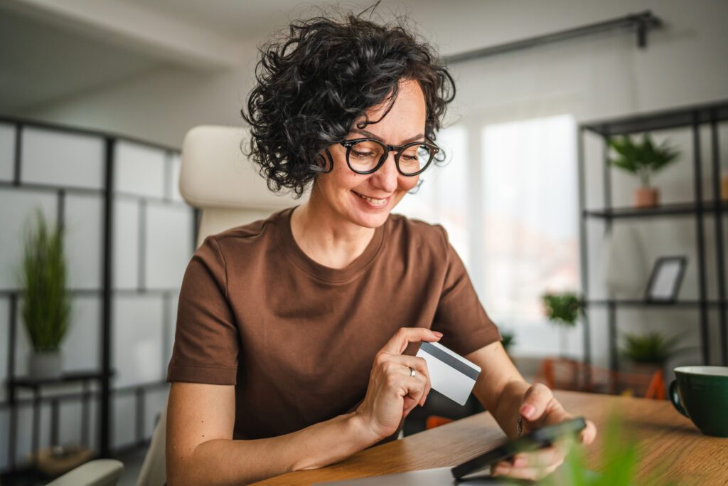 Woman smiling while using a credit card for online shopping.