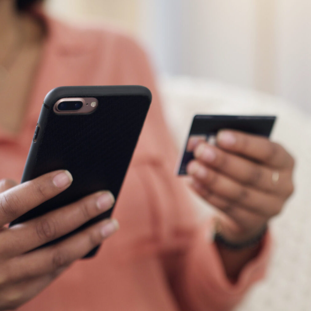 Person holding a smartphone and credit card, preparing for online payment.